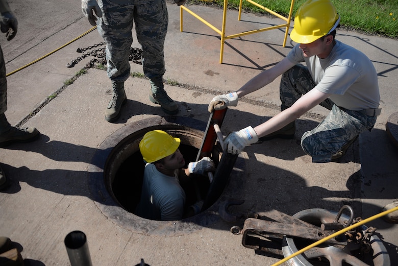 Airman 1st Class Jeffter Louzada, 364th Training Squadron cables and antenna systems apprentice course student, climbs out of a manhole with the assistance of Airman Noah Carbonaro. The manhole was in between two other manholes so a sheave and shackle had to be used that allows them to run cable through conduit and make a 90 degree turn. (U.S. Air Force photo by Senior Airman Robert L. McIlrath)