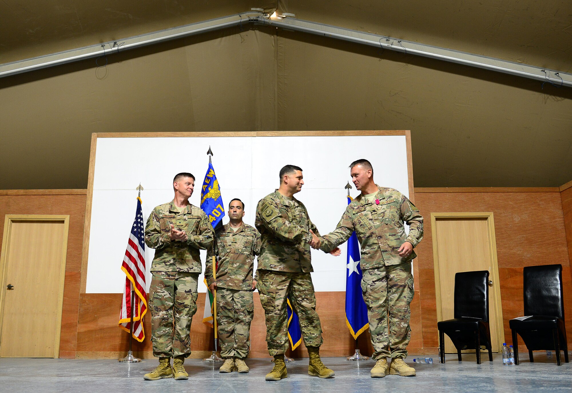 U.S. Air Force Brig. Gen. Kyle W. Robinson (left), 332nd Air Expeditionary Wing commander, Col. John F. Gonzales (center), 407th Air Expeditionary Group commander, and Col. David C. Lyons share an embrace during the 407th AEG change of command ceremony on June 17, 2017 in Southwest Asia. This ceremony signified the transfer of command between the outgoing commander Col. David C. Lyons and the incoming commander Col. John F. Gonzales to the 407th AEG. (U.S. Air Force Tech Sgt. Andy M. Kin)