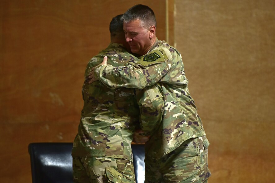 Col. John Gonzales (left) and Col. David Lyons shake hands and hug after Gonzales assumes command of the 407th Air Expeditionary Group from Lyons June 17, 2017, in Southwest Asia.Prior to inheriting the 407th AEG, Gonzales was the deputy chief of the Middle East Directorate Joint Staff J5 Iran, Iraq, Syria Division. (U.S. Air Force photo by Senior Airman Ramon A. Adelan)