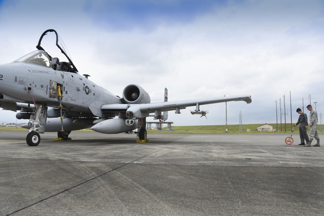 Japan Air Self-Defense Force Tech. Sgt. Hironobu Kakuta, Flight Information Squadron air operation, measures distances between aircraft to ensure there is adequate wingtip clearance during the Bilateral Exchange Program at Yokota Air Base, Japan, June 7, 2017. A total of 14 Japan Air Self-Defense Force members from a variety of career fields participated in the program. They were provided with hands-on experience working in their related fields to see how Yokota conducts its mission. (U.S. Air Force photo by Machiko Arita)