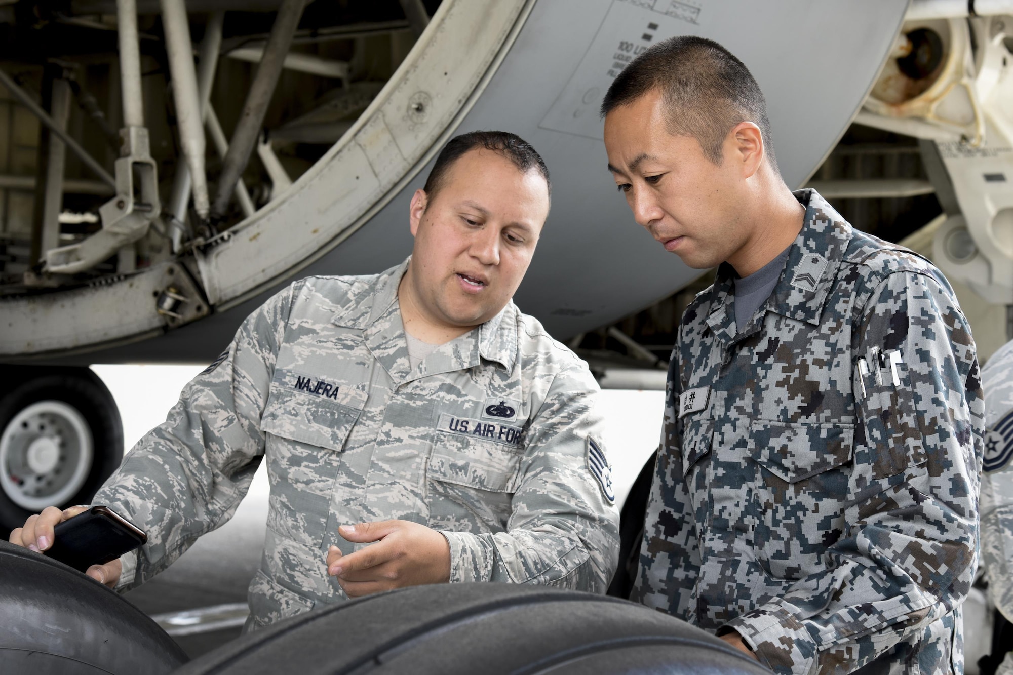 U.S. Air Force Staff Sgt. Nestor Najera, 374th Logistics Readiness Squadron rediness spares package, talks with his partner, Japan Air Self-Defense Force Tech. Sgt. Kazunori Shiroi, Central Air Defense Force Support Flight Squadron supply, after a briefing on C-5M Super Galaxy tires during the Bilateral Exchange Program at Yokota Air Base, Japan, June 8, 2017. The program allowed American and Japanese Forces the opportunity to work together and learn from each other's daily operations and build a stronger relationship. (U.S. Air Force photo by Machiko Arita)