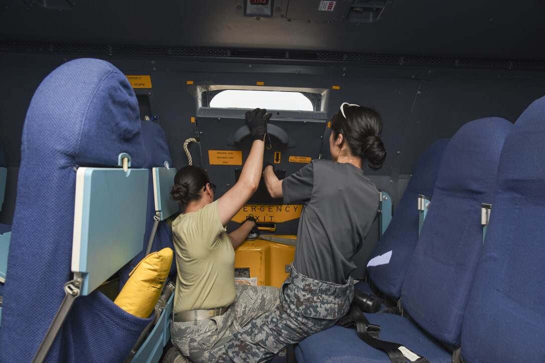 U.S. Air Force Staff. Sgt. Denisse Hernandez, 730th Air Mobility Squadron crew chief, tries to close a escape hatch with her partner, Japan Air Self-Defense Force Staff. Sgt. Akiko Miyamae, Central Air Defense Force Support Flight Squadron aircraft maintenance, during the Bilateral Exchange Program at Yokota Air Base, Japan, June 8, 2017. The program allowed American and Japanese Forces the opportunity to work together and learn from each other's daily operations and build a stronger relationship. (U.S. Air Force photo by Machiko Arita)