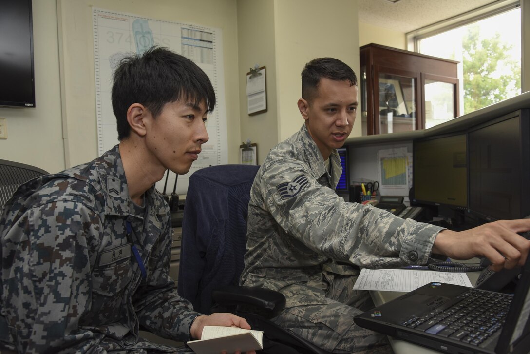 U.S. Air Force Staff Sgt. Michael Ober, 374th Operation Support Squadron NCO in charge of
airfield management training, explains his unit's flight planning to Japan Air Self-Defense Force Tech. Sgt. Hironobu Kakuta, Flight Information Squadron air operation, during the Bilateral Exchange Program at Yokota Air Base, Japan, June 7, 2017. A total of 14 Japan Air Self-Defense Force members from a variety of career fields participated in the program. They were
provided with hands-on experience working in their related fields to see how Yokota conducts its mission. (U.S. Air Force photo by Machiko Arita)