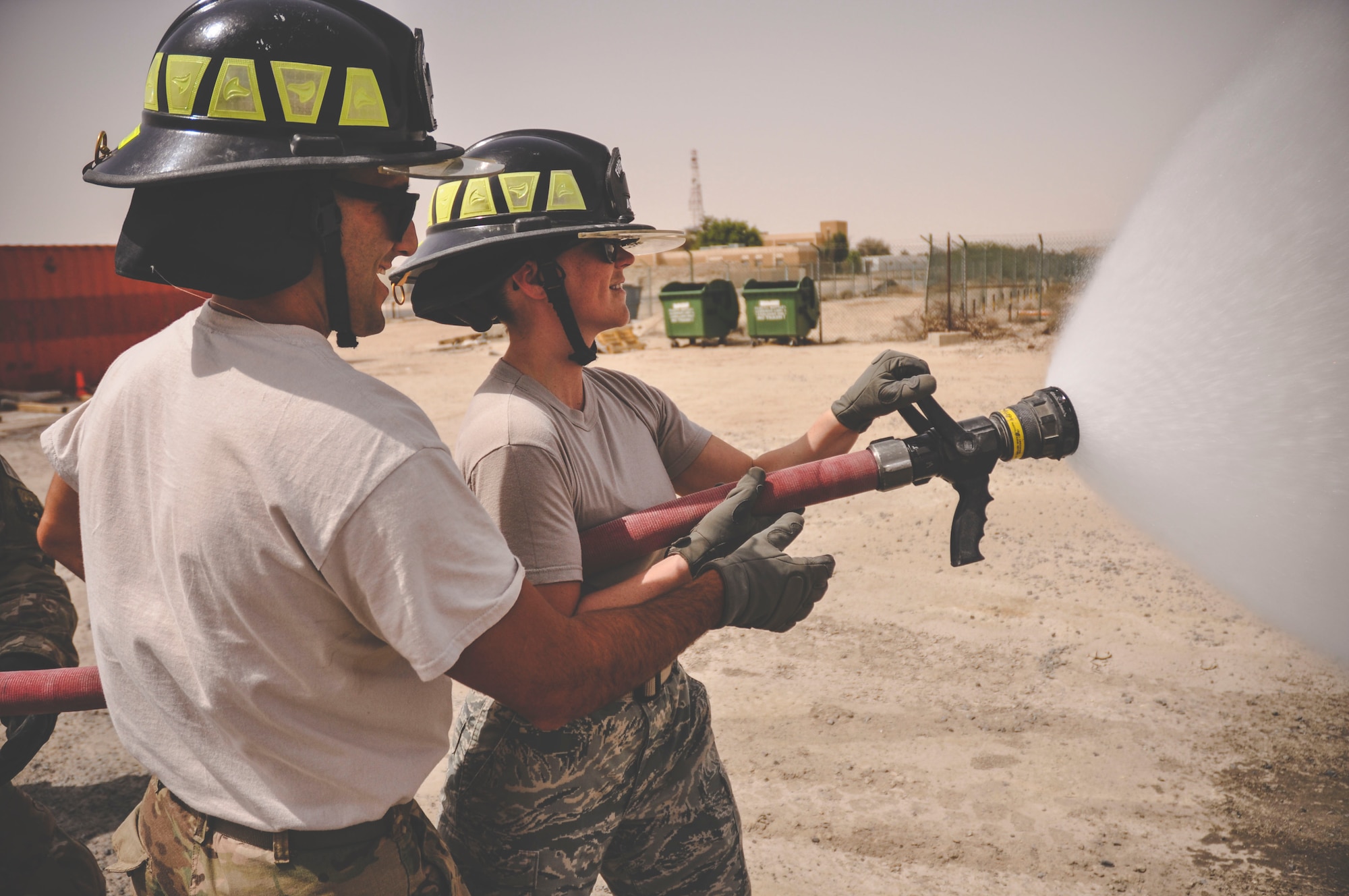 Senior Airman Kevin Angelesco, a fire fighter assigned to the 386th Expeditionary Civil Engineer Squadron (left) supervises Staff Sgt. Jessica Moore, a mental health technician with the 386th Medical Group as she learns how to control a fire hose during a mental health unit familiarization visit at an undisclosed location in southwest Asia, May 30, 2017. Angelesco is a reservist deployed from the 940th Civil Engineer Squadron, Beale Air Force Base, Calif.(U.S. Air Force Photo/Master Sgt. Eric M. Sharman)