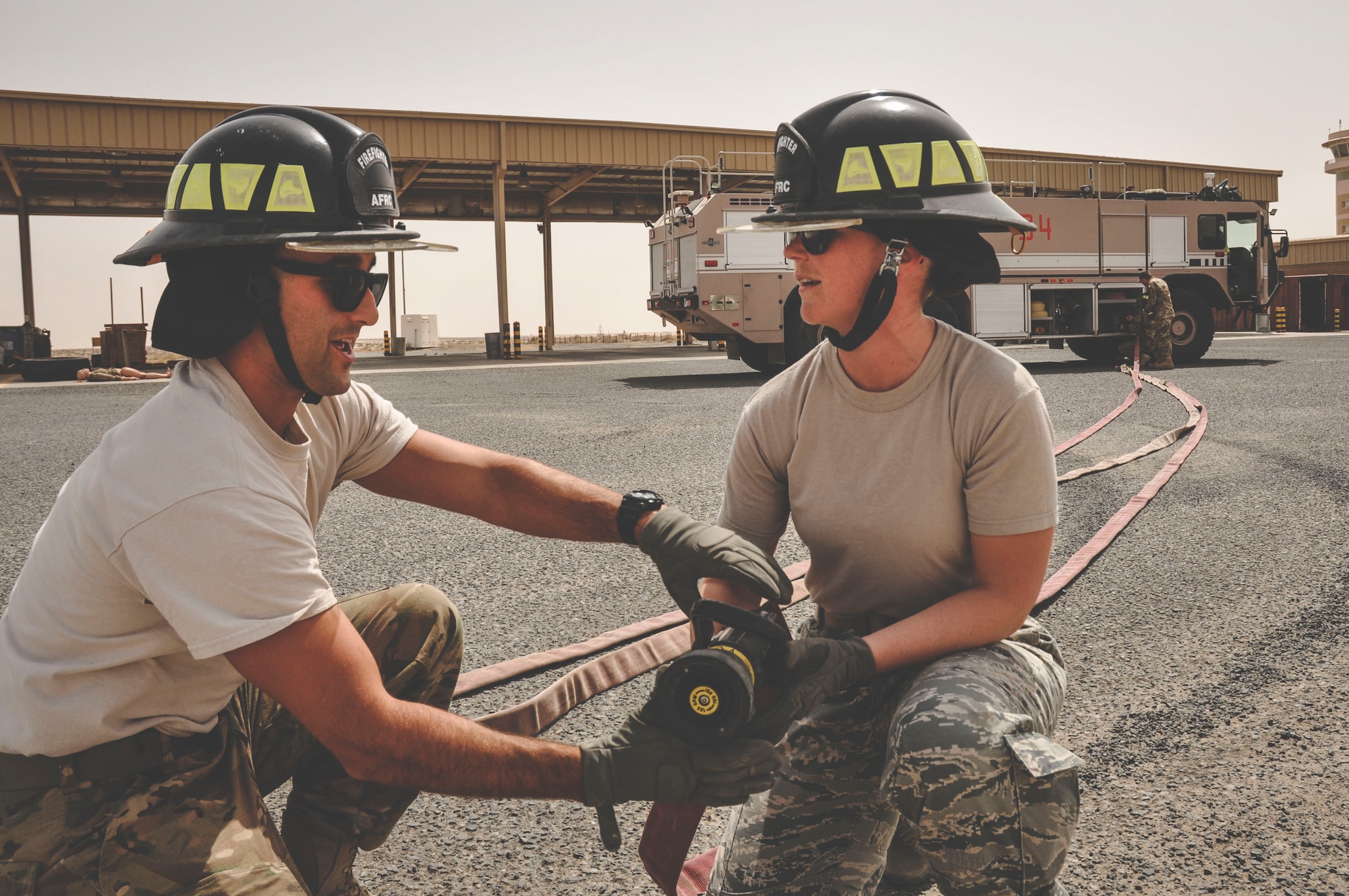 Senior Airman Kevin Angelesco a fire fighter assigned to the 386th Expeditionary Civil Engineer Squadron, (left) instructs Staff Sgt. Jessica Moore, a mental health technician with the 386th Medical Group on fire hose control during a mental health unit familiarization visit at an undisclosed location in southwest Asia, May 30, 2017. Moore regularly conducts unit visits to perform preventative mental health checks. (U.S. Air Force Photo/Master Sgt. Eric M. Sharman)