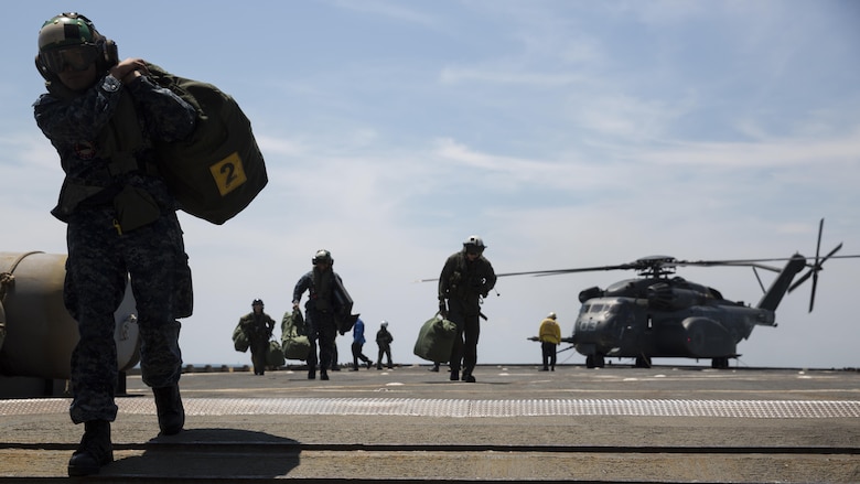 Sailors debark an MH-53 helicopter and unload gear aboard the USS Whidbey Island, June 13, 2017. Military personel all across the department of defense are making preparations for Sail Boston 2017 to showcase their vast cabailities to the public. The sailors boarded the ship to display an MH-53 helicopter during the festivities. The sailors are assigned to HM15.