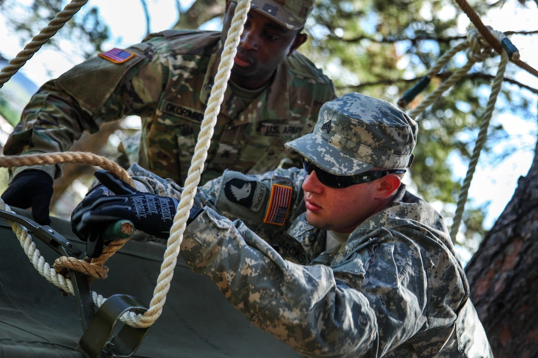 Missouri Army National Guard Sgt. Chima Okorafor, left, and Sgt. Mike Jackson tie a rope in an effort to assist soldiers across an obstacle during the Leadership Reaction Course in support of exercise Golden Coyote, Rapid City, S.D., June 13, 2017. Okorafor and Jackson are assigned to the 1138th Transportation Company. A three-phase, scenario-driven exercise conducted in the Black Hills of South Dakota and Wyoming, Golden Coyote enables commanders to focus on mission essential task requirements, warrior tasks and drills. Army photo by Spc. Jeffery Harris