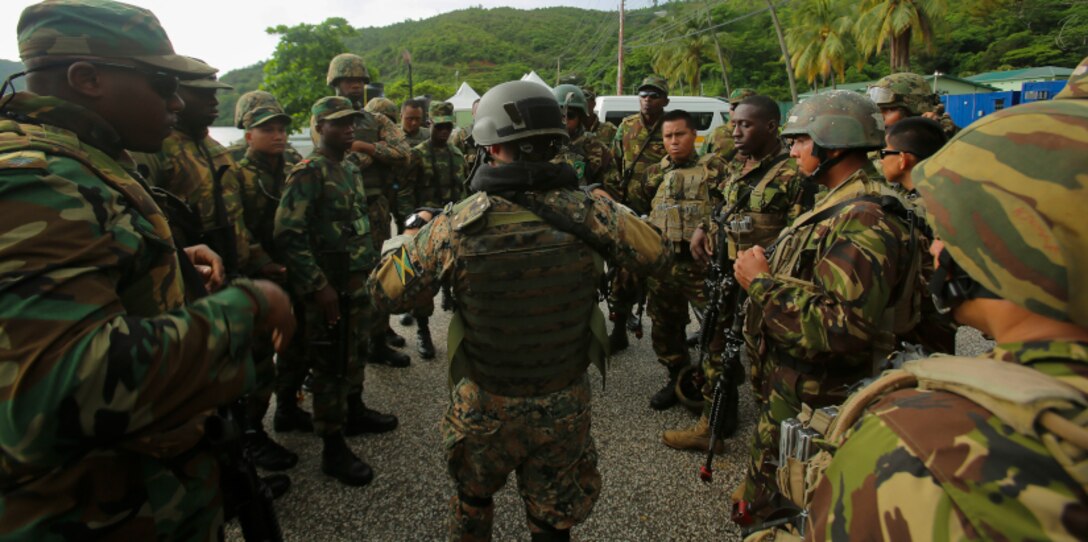 Service members from Belize, Jamaica, Trinidad and Tobago, and Mexican Marines discuss the objective before conducting a simulated raid on a hangar during Phase II of Exercise Tradewinds 2017 in Chaguaramas, Trinidad and Tobago, June 14, 2017. Tradewinds, sponsored by U.S. Southern Command, is an annual combined exercise designed to increase Caribbean security by enhancing the collective ability of the 20 participating nations to counter transnational organized crime and terrorism, and conduct humanitarian assistance and disaster relief operations. U.S. Marines are providing training and logistical support for Phase II of Tradewinds. (U.S. Marine Corps photo by Cpl. Luke Hoogendam)