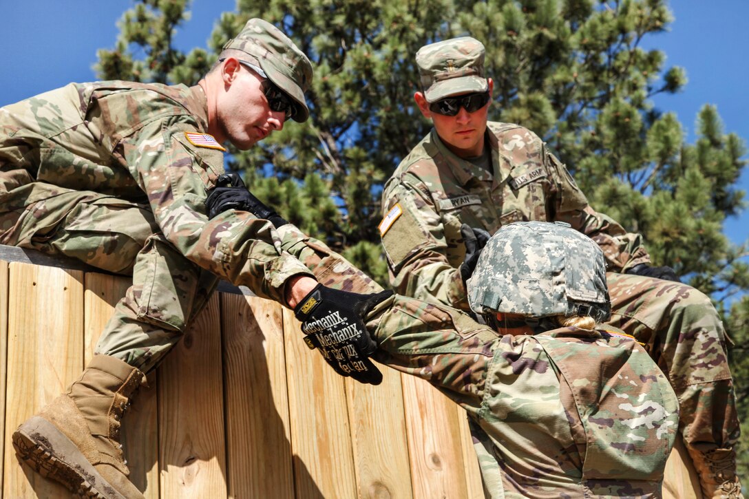 Army Spc. Christopher Bodimer, left, and 2nd Lt. Neal Ryan, right, assist Spc. Hannah Turner over a wall obstacle during the Leadership Reaction Course in support of exercise Golden Coyote, Rapid City, S.D., June 13, 2017. Bodimer, Ryan and Turner are assigned to the 1138th Transportation Company, Missouri Army National Guard. Army photo by Spc. Jeffery Harris