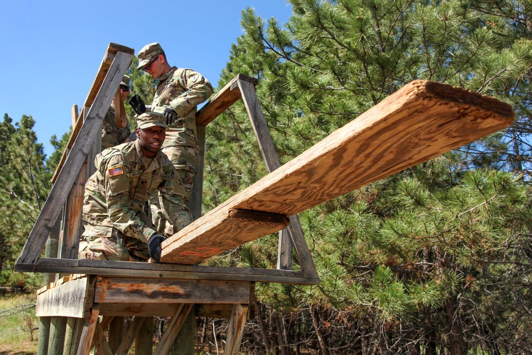 Army Spc. Timothy Manuel stretches out planks of wood in an attempt to cross the obstacle in the Leadership Reaction Course in support of exercise Golden Coyote, Rapid City, S.D., June 13, 2017. Army photo by Spc. Jeffery Harris  