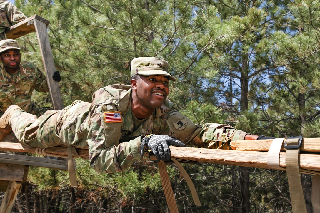 Army Pvt. Antonio Johnson crawls over a plank bridge during the Leadership Reaction Course in support of exercise Golden Coyote, Rapid City, S.D., June 13, 2017. Johnson is assigned to the 1138th Transportation Company, Missouri Army National Guard. Army photo by Spc. Jeffery Harris