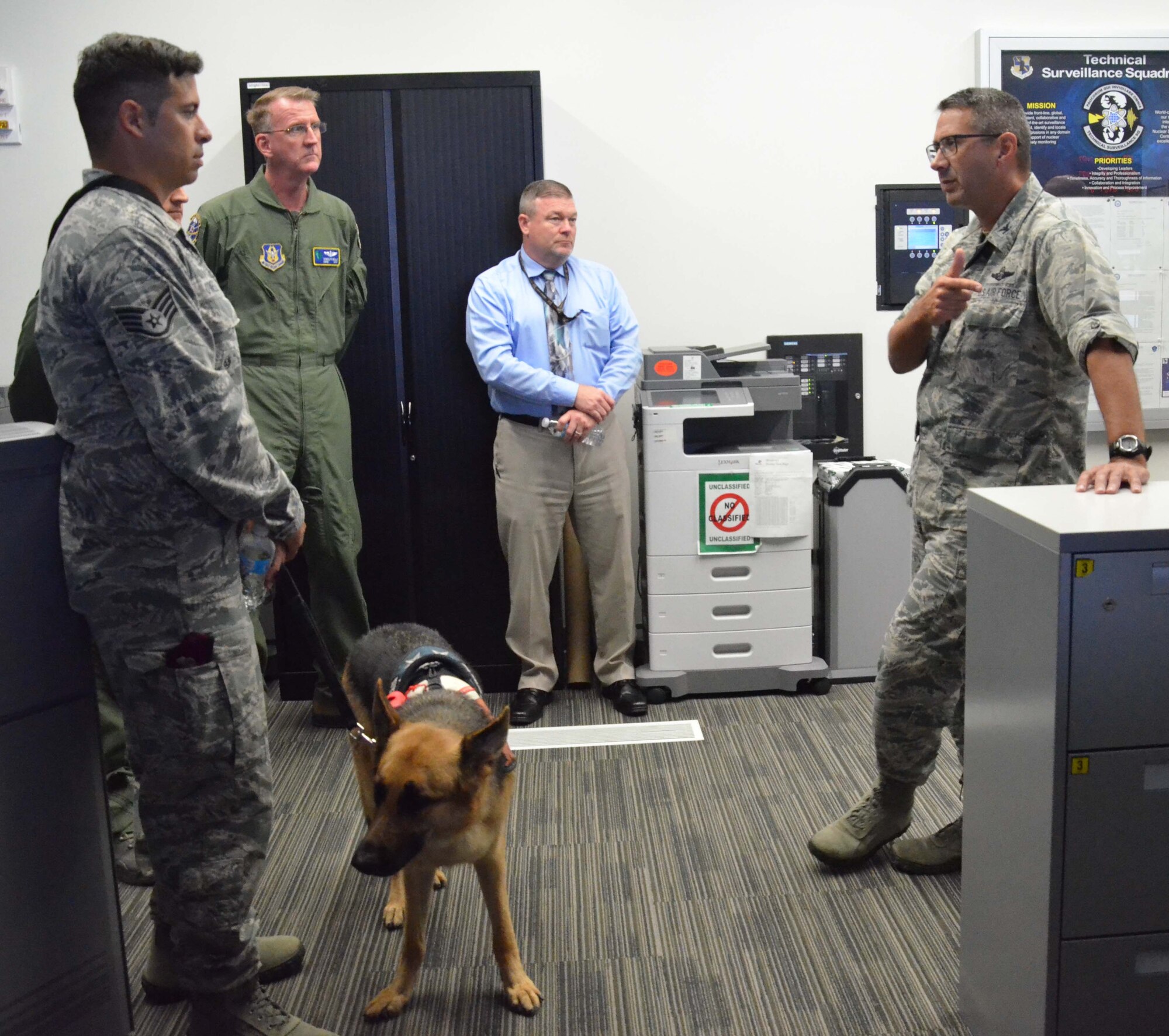 Col. Jon VanNoord (right), director of operations for the Air Force Technical Applications Center, Patrick AFB, Fla., briefs Staff. Sgt. August O’Niell (left), the Air Force’s first pararescue amputee, during O’Niell’s visit to the nuclear treaty monitoring center May 22, 2017.  Pictured with O’Niell is his service dog and constant companion, Kai.  (U.S. Air Force photo by Susan A. Romano)