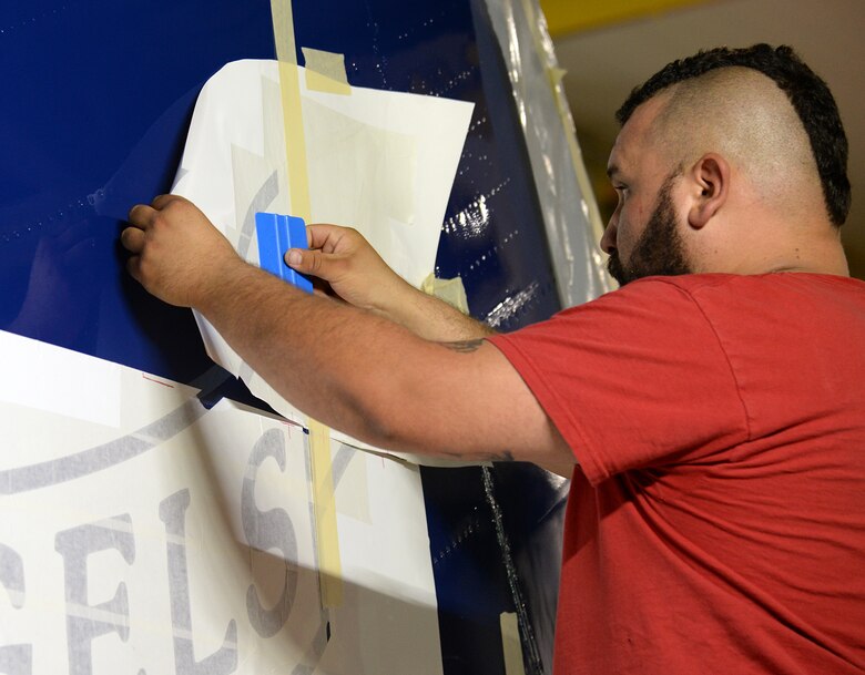 Richard Barber, 576th Aircraft Maintenance Squadron painter, applies a masking stencil to the vertical stabilizer of Fat Albert on May 23 at Hill Air Force Base, Utah. The stencil is part of the main Blue Angels logo painted on the aircraft. (U.S. Air Force Photo by Alex R. Lloyd)
