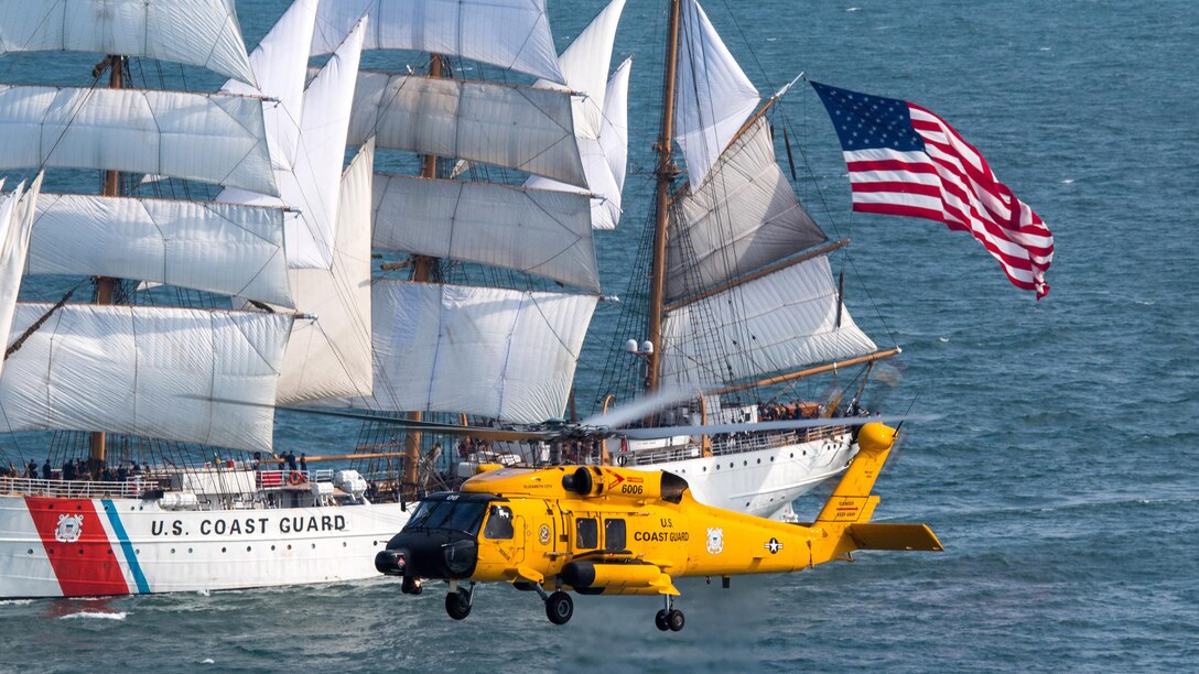 A Coast Guard MH-60 Jayhawk helicopter flies beside the Coast Guard Cutter Eagle in Norfolk, Va., June 12, 2017. U.S. Coast Guard Academy cadets train aboard the Eagle to learn historic aspects of sailing, leadership, navigation and teamwork. Coast Guard photo by Auxiliarist David Lau