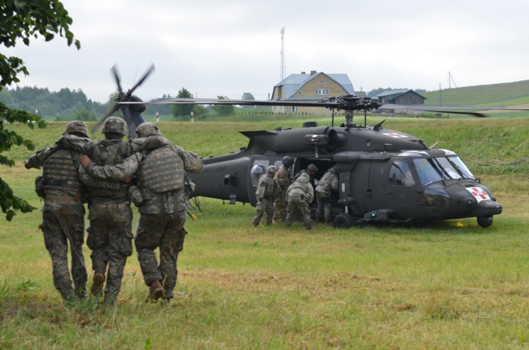 A combined forces squad featuring members of the Minnesota Army National Guard's 1st Armored Brigade Combat Team, 34th Infantry Division, British Royal Marines and Polish soldiers transport a simulated casualty to an HH-60M Black Hawk helicopter after a ground assault exercise transitioned into a medical evacuation exercise near Sventezeris, Lithuania, June 18, 2017. The training was part of Exercise Saber Strike 17, a U.S. Army Europe-led training exercise in the Baltic region. The exercise tests the capability of multiple nations to act against a threat. Army photo by Sgt. Shiloh Capers