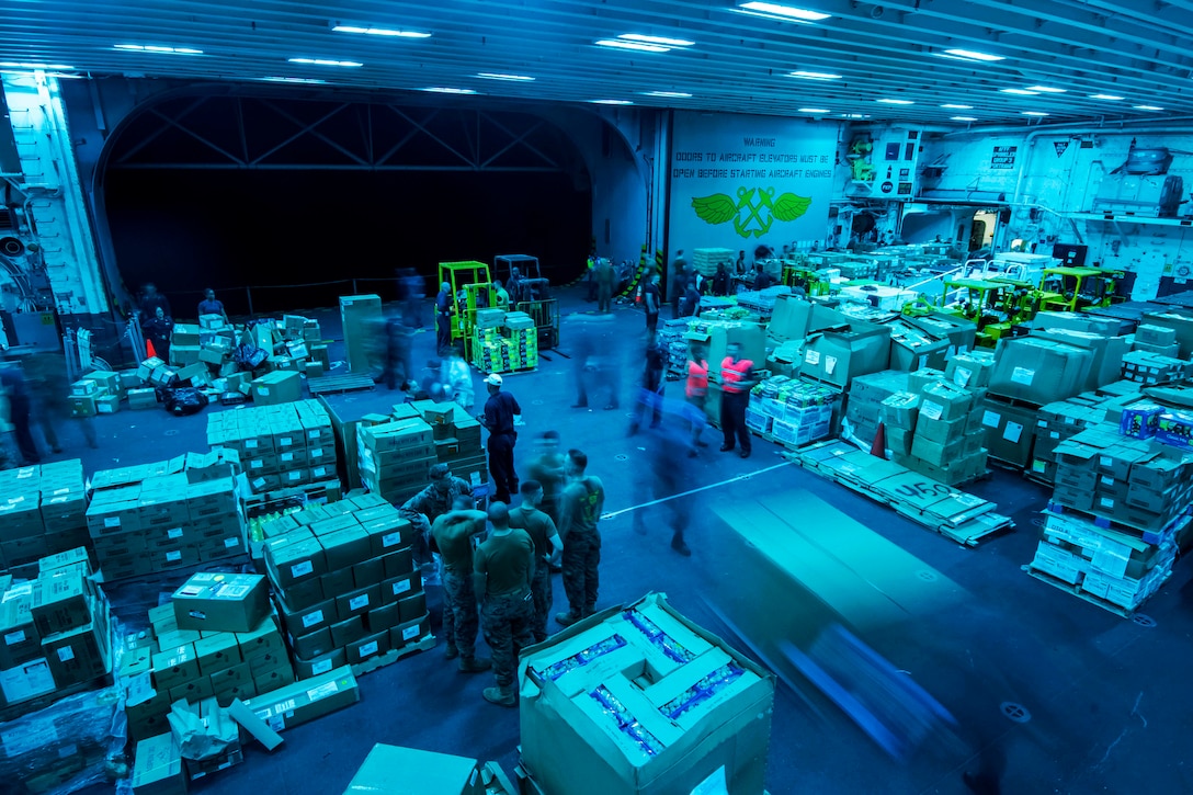 Sailors and Marines aboard the amphibious assault ship USS Bonhomme Richard store 400 pallets of supplies in the hangar bay during a replenishment at sea in the Philippine Sea, June 16, 2017. Navy photo by Petty Officer 2nd Class Jeanette Mullinax