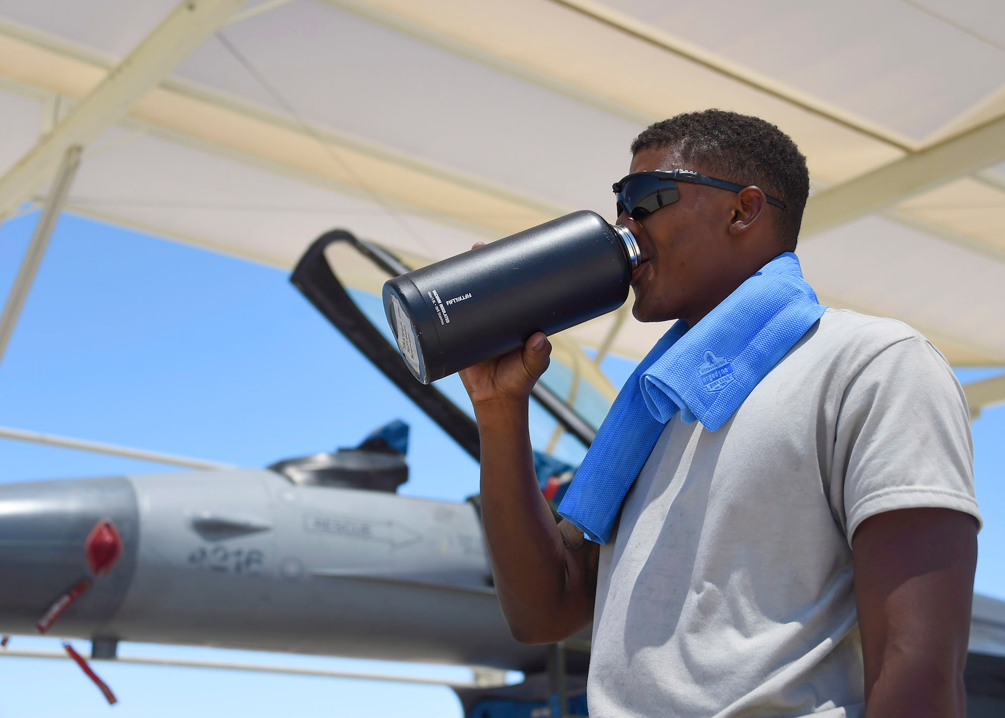 Senior Airman Lakenzar Snipes, 309th Aircraft Maintenance Unit crew chief, takes a water break while maintaining an F-16 June 15, 2017, at Luke Air Force Base, Ariz. With temperatures exceeding 100 degrees, sunshades keep both the Airmen who maintain the aircraft and the jets themselves cooler. (U.S. Air Force photo by Senior Airman James Hensley)
