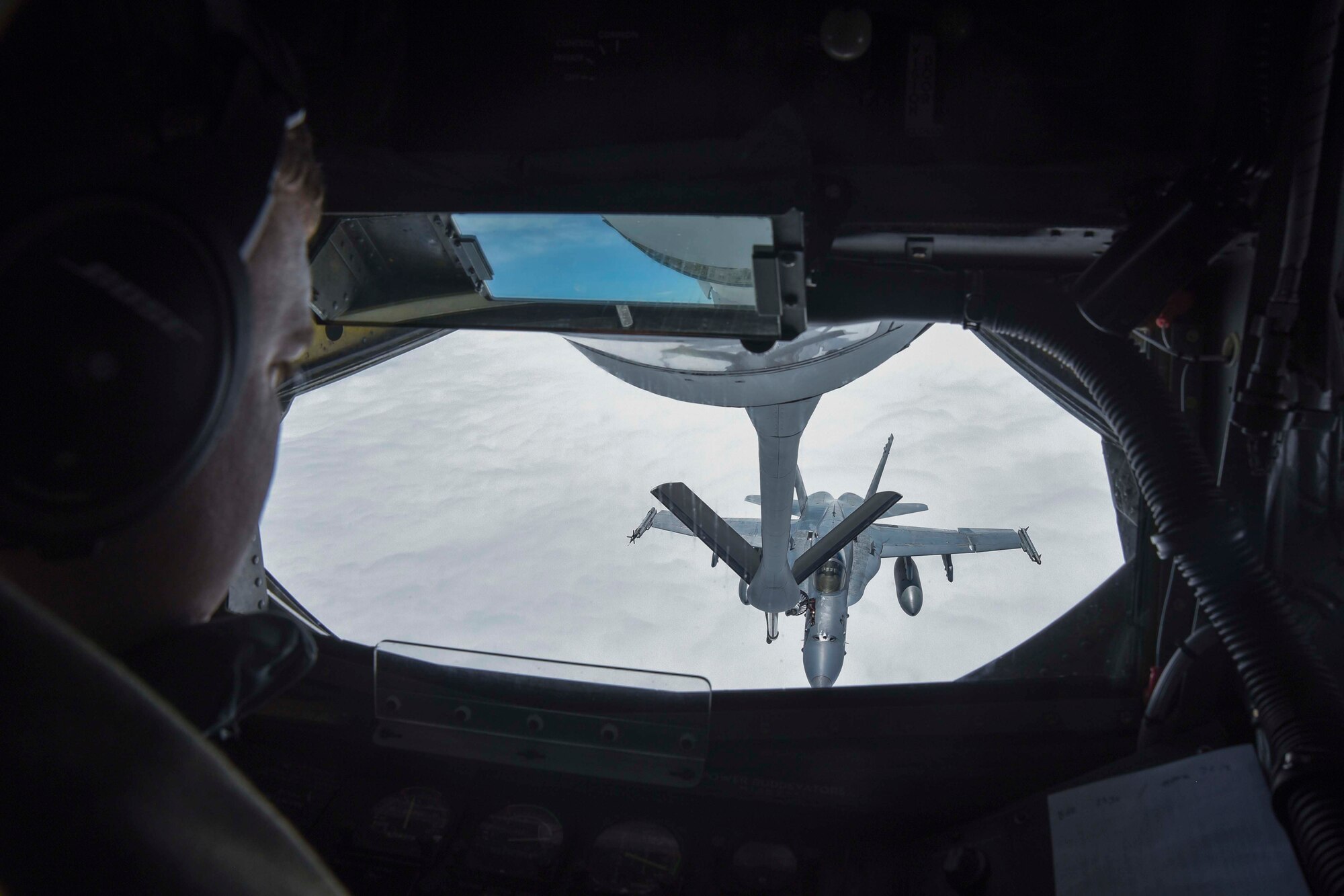Senior Airman Jeffrey Jaskela, 350th Air Refueling Squadron boom operator, refuels an F-18 Hornet, above Canada, during Red Flag-Alaska 17-2, June 12, 2017. Four McConnell aircrew took two KC-135 Stratotankers to Eielson Air Force Base, Alaska, to provide warfighting support during the two-week exercise. (U.S. Air Force photo/Senior Airman Chris Thornbury)