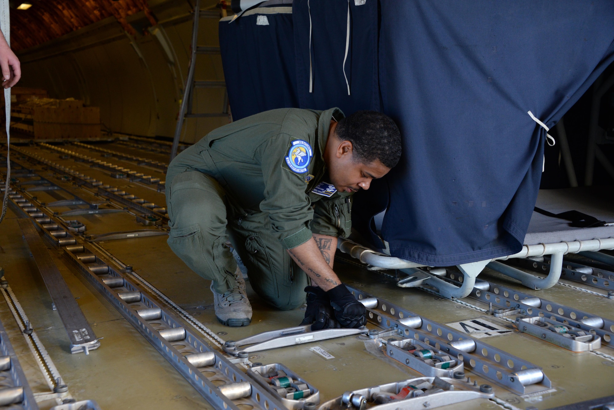 Tech. Sgt. Lee Crawford, 6th Air Refueling Squadron, configures the floor of a KC-10 Extender prior to loading operations at Travis Air Force Base, Calif., June 17, 2017. Crawford helped load more than 15,000 pounds of cargo prior to a flight to Joint Base Pearl Harbor-Hickam, Hawaii. (U.S. Air Force photo by Tech. Sgt. James Hodgman)