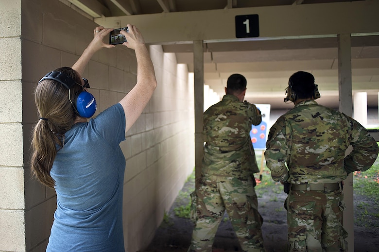 Christie Patterson, the wife of a Special Operations Command Central (SOCCENT) service member, takes a photo of her husband firing a handgun during Spartan Spouse Day at MacDill Air Force Base, June 13, 2017. During the day, spouses of SOCCENT members learned how to properly load, fire and unload a handgun. (U.S. Air Force photo by Airman 1st Class Caleb Nunez)