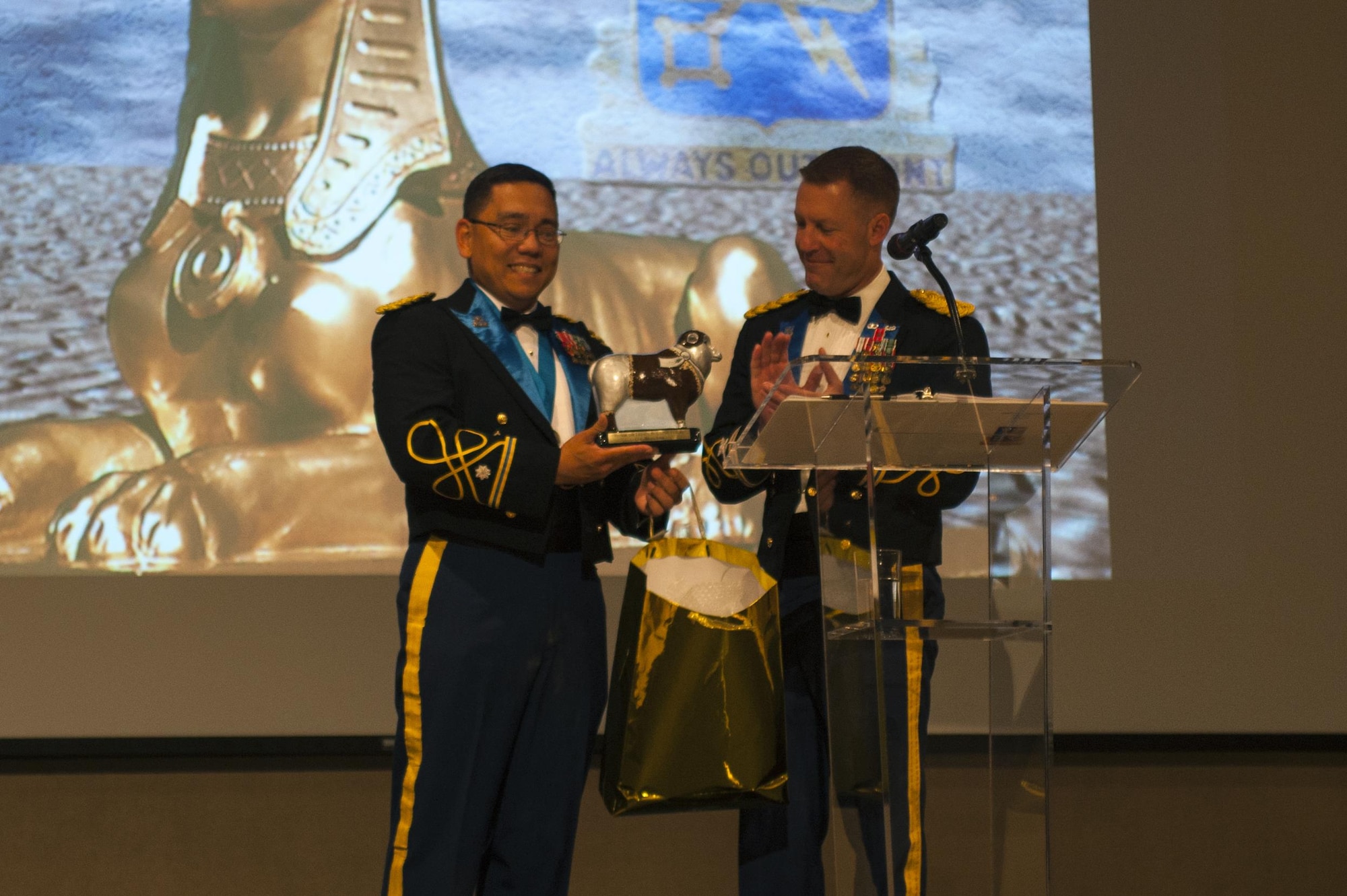 U.S. Army Lt. Col. Yukio Kuniyuki, 344th Military Intelligence Battalion Commander, gifts a Lt. Col. Ewe Little figurine to Col. Brian Lieb, during the Army Ball at the McNease Convention Center San Angelo, Texas, June 16, 2017. Ewe Little is a sheep statue posted outside Goodfellow Air Force Base, a gift from the local city San Angelo. San Angelo at one point had a massive sheep population and the sheep has since become the city’s mascot. Every organization gifted a sheep by the city has their own design. (U.S. Air Force photo by Senior Airman Scott Jackson/Released)