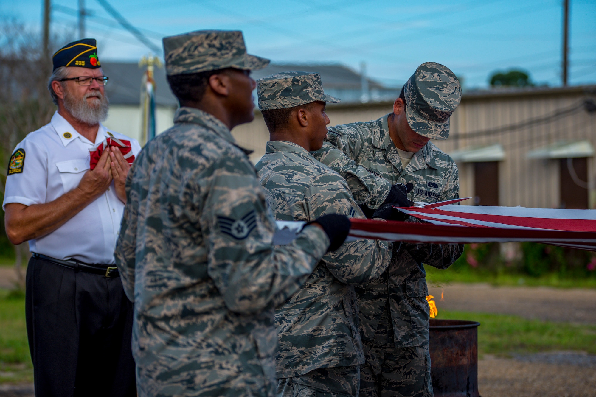 Senior Airman Anthony Padilla, 96th Aircraft Maintenance Squadron, cuts the individual stripes from a flag during a flag retirement ceremony at American Legion Post 235 in Fort Walton Beach, June 14. Cutting the red and white stripes, renders it no longer a flag. When a flag is worn beyond repair, it should be retired in a dignified manner. Honor Guards from Eglin Air Force Base and Hurlburt Field participated in the observance dating back to 1937. (U.S. Air Force photo/Kristin Stewart)