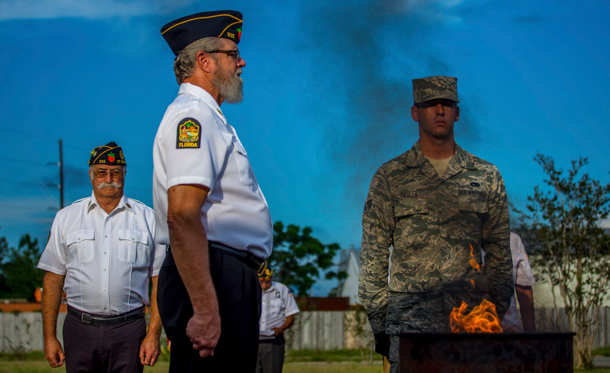 Senior Airman Antony Padilla, 96th Aircraft Maintenance Squadron, stands at attention with American Legion members as a unserviceable flag burns during a flag retirement ceremony at American Legion Post 235 in Fort Walton Beach on Flag Day, June 14. Honor Guards from Eglin Air Force Base and Hurlburt Field participated in the observance dedicated to the dignified retirement of worn and tattered flags no longer suitable to represent the nation. (U.S. Air Force photo/Kristin Stewart)