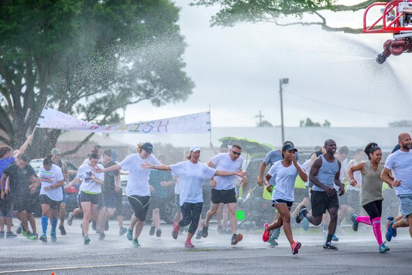 Runners sprint through a fire engine sprinkler manned by 96th Civil Engineer Group firefighters at the start line during the LGBT Pride Month 5K Color Run June 14 at Eglin Air Force Base, Fla. The run was held to celebrate diversity and to raise inclusion awareness. (U.S. Air Force photo/Kristin Stewart)