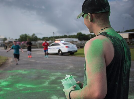 A volunteer stands ready with his containers of colored chalk as runners approach the finish line during the LGBT Pride Month 5K Color Run June 14 at Eglin Air Force Base, Fla. The run was held to celebrate diversity and to raise inclusion awareness. (U.S. Air Force photo/Ilka Cole)