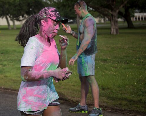 A runner covered in colored chalk uses her fingers to remove the the color from her mouth as she approaches the finish line during the LGBT Pride Month 5K Color Run June 14 at Eglin Air Force Base, Fla. The run was held to celebrate diversity and to raise inclusion awareness. (U.S. Air Force photo/Ilka Cole)