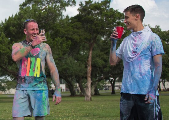 A runner covered in color captures a photo of his friend sipping water at the end of the LGBT Pride Month 5K Color Run June 14 at Eglin Air Force Base, Fla. The run was held to celebrate diversity and raise inclusion awareness. (U.S. Air Force photo/Ilka Cole)