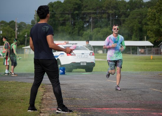 Airman 1st Class Carladrien Aguilar, volunteer from the 96th Logistics Readiness Squadron, readies his container of colored chalk as runners approach during the LGBT Pride Month 5K Color Run June 14 at Eglin Air Force Base, Fla. The run was held to celebrate diversity and to raise inclusion awareness. (U.S. Air Force photo/Ilka Cole)