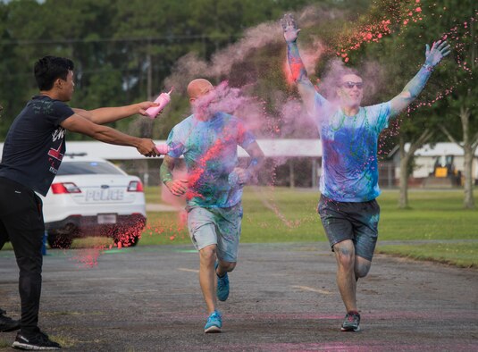 Airman 1st Class Carladrien Aguilar, volunteer from the 96th Logistics Readiness Squadron, squeezes a container of colored chalk at runners during the LGBT Pride Month 5K Color Run June 14 at Eglin Air Force Base, Fla. The run was held to celebrate diversity and to raise inclusion awareness. (U.S. Air Force photo/Ilka Cole)