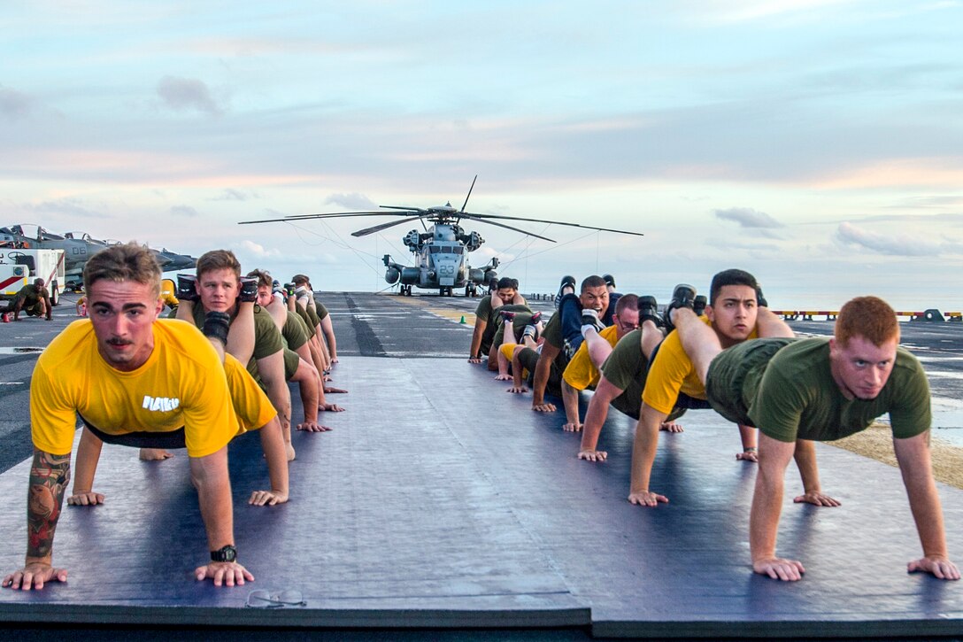 Marines and sailors participate in physical training on the flight deck of the amphibious assault ship USS Bonhomme Richard in the Bismark Sea, June 19, 2017. The Bonhomme Richard is operating in the Indo-Asia-Pacific region to enhance partnerships and serve as a ready-response force for any type of contingency. Navy photo by Seaman Apprentice Gavin Shields