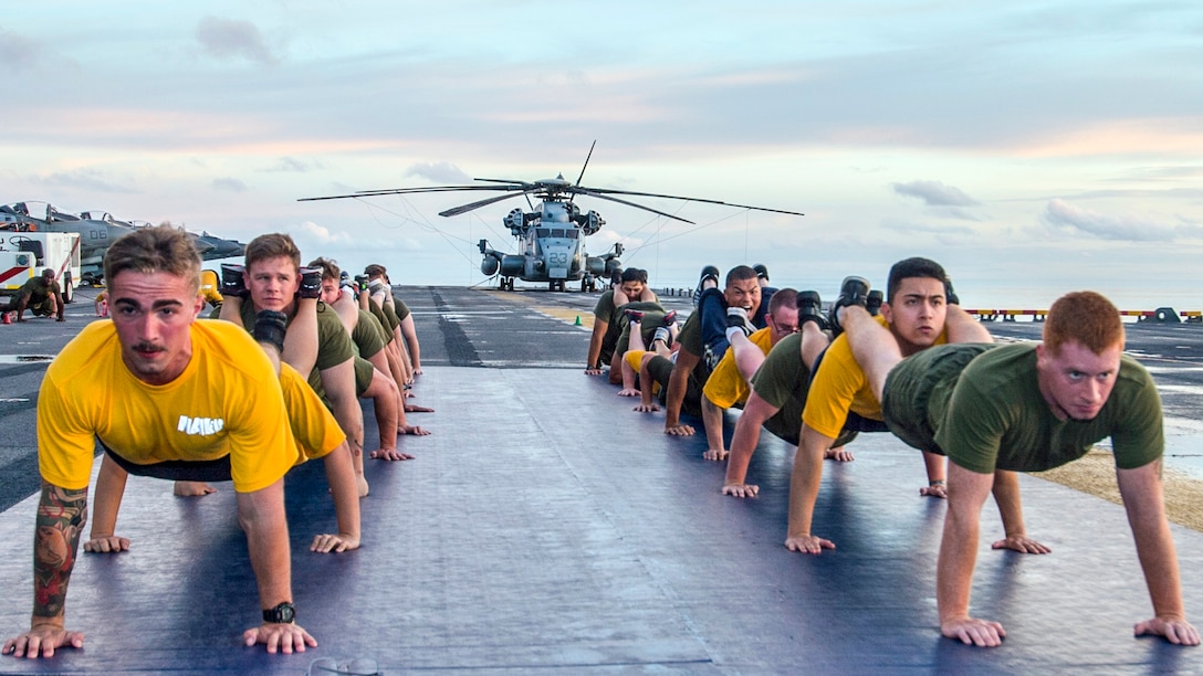 Marines and sailors participate in physical training on the flight deck of the amphibious assault ship USS Bonhomme Richard in the Bismark Sea, June 19, 2017. The Bonhomme Richard is operating in the Indo-Asia-Pacific region to enhance partnerships and serve as a ready-response force for any type of contingency. Navy photo by Seaman Apprentice Gavin Shields