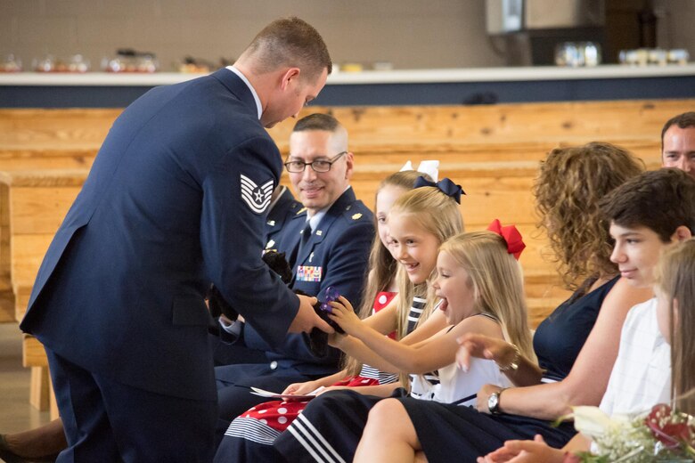 Tech. Sgt. Joseph Berglund, 43d Operations Support Squadron, presents small stuffed panthers to the daughters of Lt. Col. Judd Baker, welcoming them to the 43d OSS panther family during a change-of command ceremony here June 9. Bake took command of the unit during the ceremony. (U.S. Air Force photo/Marc Barnes)