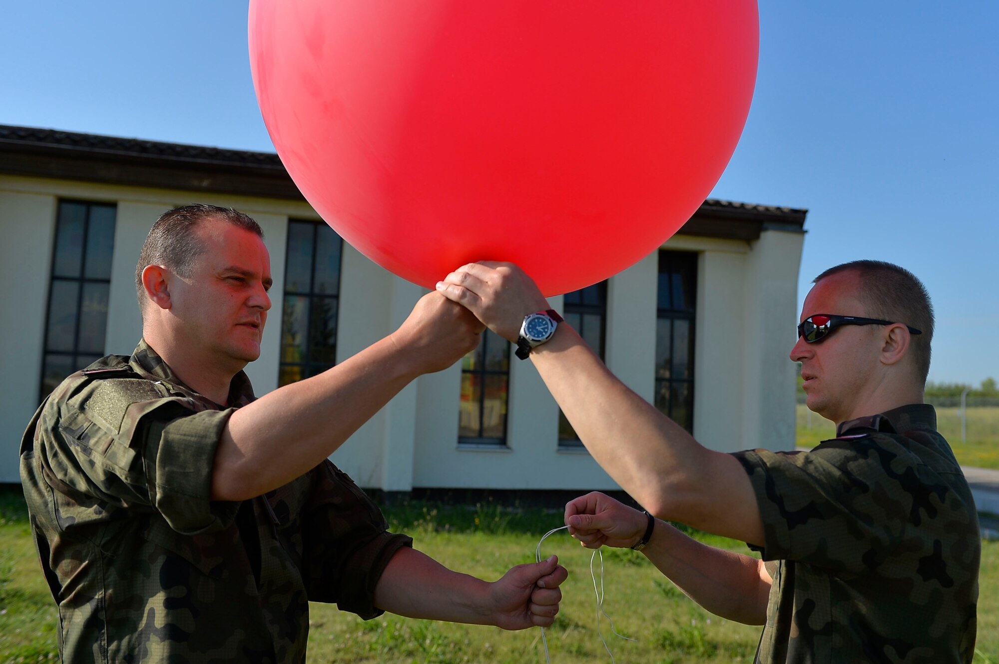Polish Air Force Warrant Officers Jaroslaw Engelgardt, left, and Marcin Galek, both weathermen, tie a weather balloon at McCully Barracks, Germany, June 15, 2017. NATO allies at the 7th Weather Squadron’s Exercise Cadre Focus 17-1 showcased their weather operations capabilities. Ramstein Airmen  and allies from Germany, Poland, and Hungary aimed to enhance interoperability through information exchange. (U.S. Air Force photo by Airman 1st Class Joshua Magbanua)