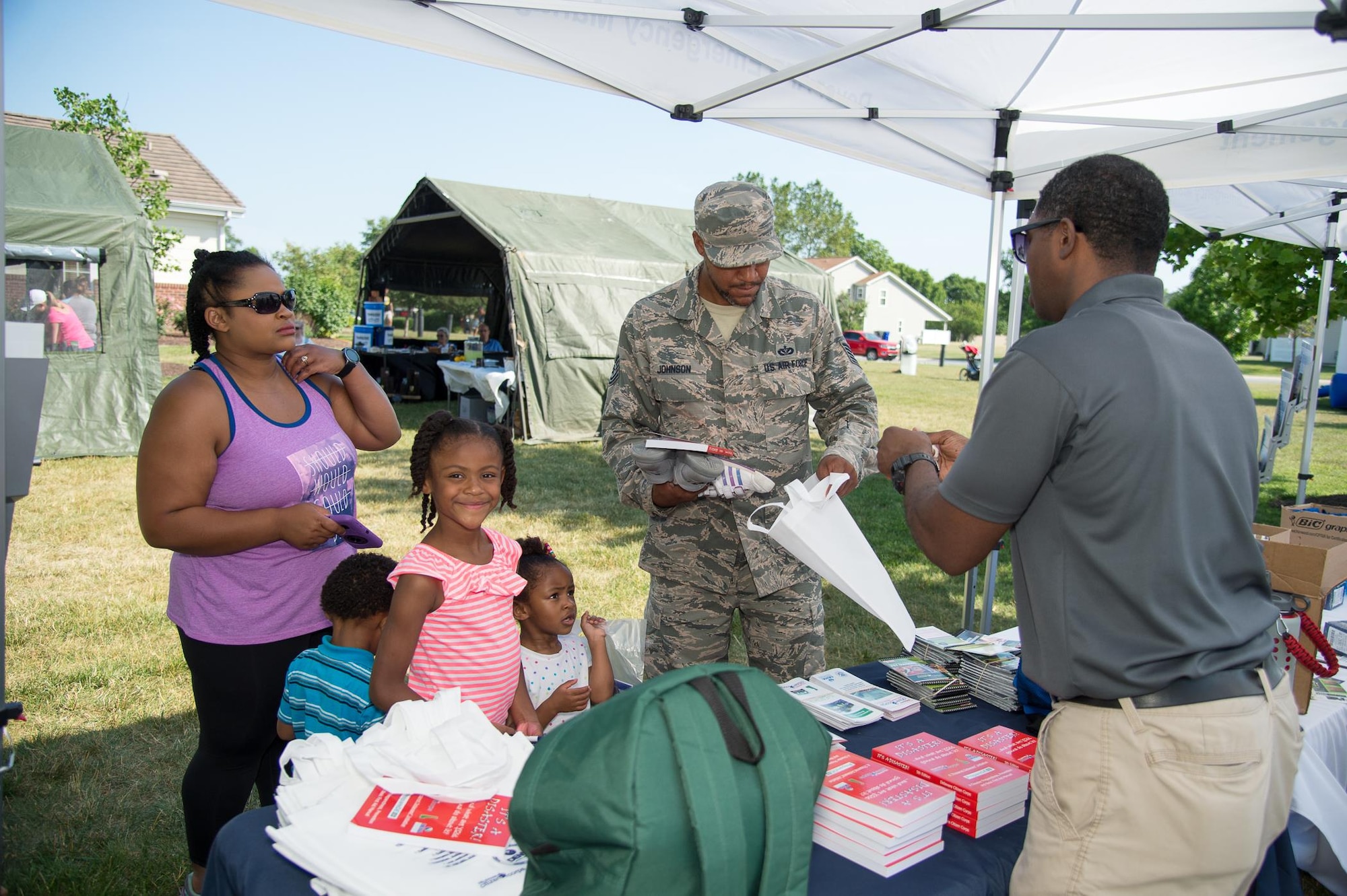 Tech Sgt. Michael Johnson II, 436th Civil Engineering Squadron electrical systems craftsman, and his family receive an information packet on emergency procedures at the Hurricane Block Party June 15, 2017, in Eagle Heights family housing on Dover Air Force Base, Del. Sponsored by the 436th Civil Engineering Squadron Emergency Management Flight, the block party offered attendees useful information pertaining to severe storms and hurricanes. (U.S. Air Force photo by Mauricio Campino)