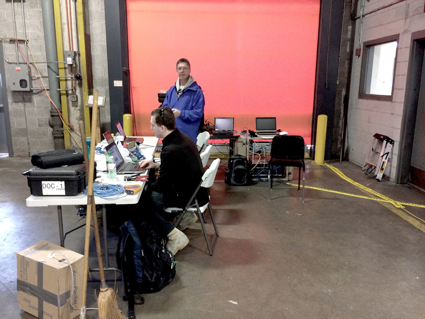 Contingency Information Technology Team members Sean Mace (seated) and John Wolk perform operational checks on Information Operations Deployable Operations Center equipment.