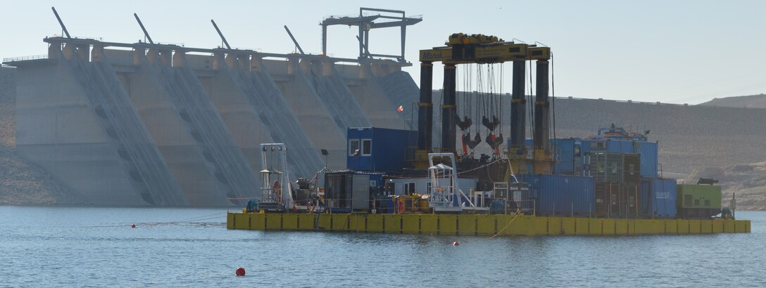 Rick Benoit, Portland District dive team proponent and program manager, and the bottom outlet team conduct dives from this barge in front of Mosul Dam, Iraq. The team is inspecting a pair of underwater tunnels, which regulates the water depth in Lake Dahuk, the upstream reservoir and the Tigris River. (Corps of Engineers Photo)