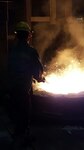 A Buck Company employee stirring molten metal to pull out impurities.