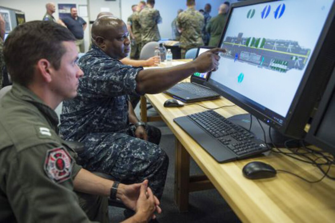 Lt. Timothy Sullivan, left, and Chief Warrant Officer 3 Chuck Broadous, both assigned to the amphibious assault ship USS Iwo Jima , test the  Office of Naval Research Tech Solutions-sponsored Deployable Ship Integration Multi-touch System during pre-deployment training. Navy photo by John F. Williams