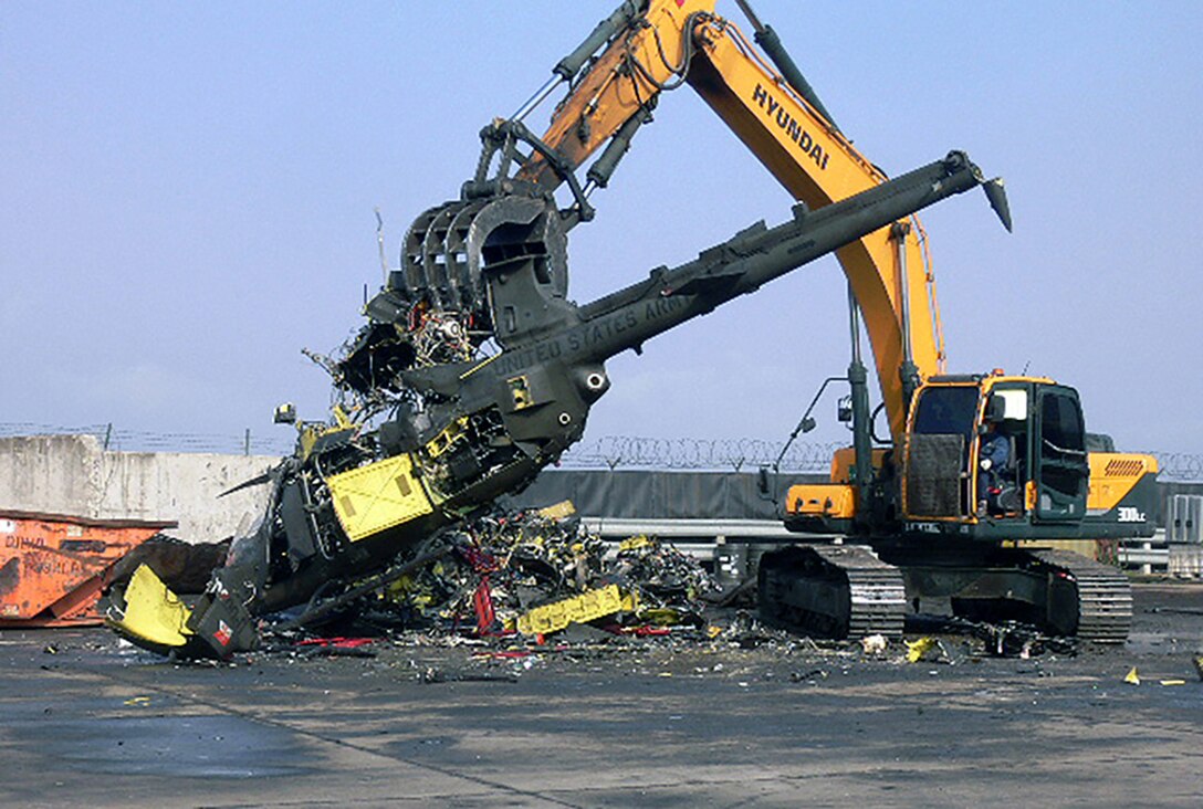 A contractor employs uses an excavator to break up one of 27 OH-58 Kiowa Warrior aircraft at Gimcheon, Korea.