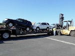 Workers load three 2008 Ford Escapes for their long journey from Hawaii to Moldova.