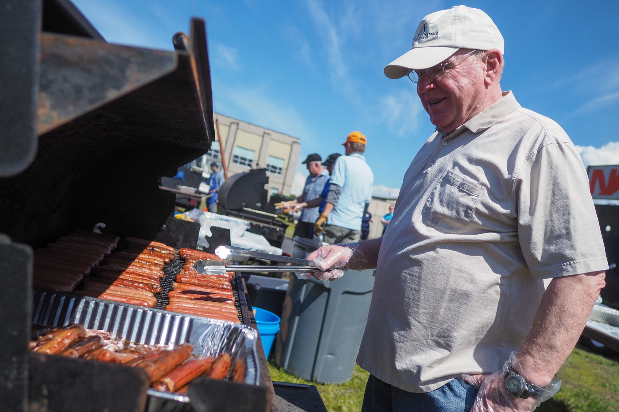 Chris Nelson, of Anchorage, representing the Association of the United States Army, grills hot dogs as service members, dependents, and Department of Defense civilians attend the Military Appreciation Week picnic at the Joint Base Elmendorf-Richardson, Alaska, Buckner Fitness Center fields June 16, 2017. Several organizations came together to provide a variety of family-fun activities such as competitive sporting events for the adults, face painting and bouncy houses for the children in addition to the Anchorage Chamber of Commerce-provided food and music during the annual event.