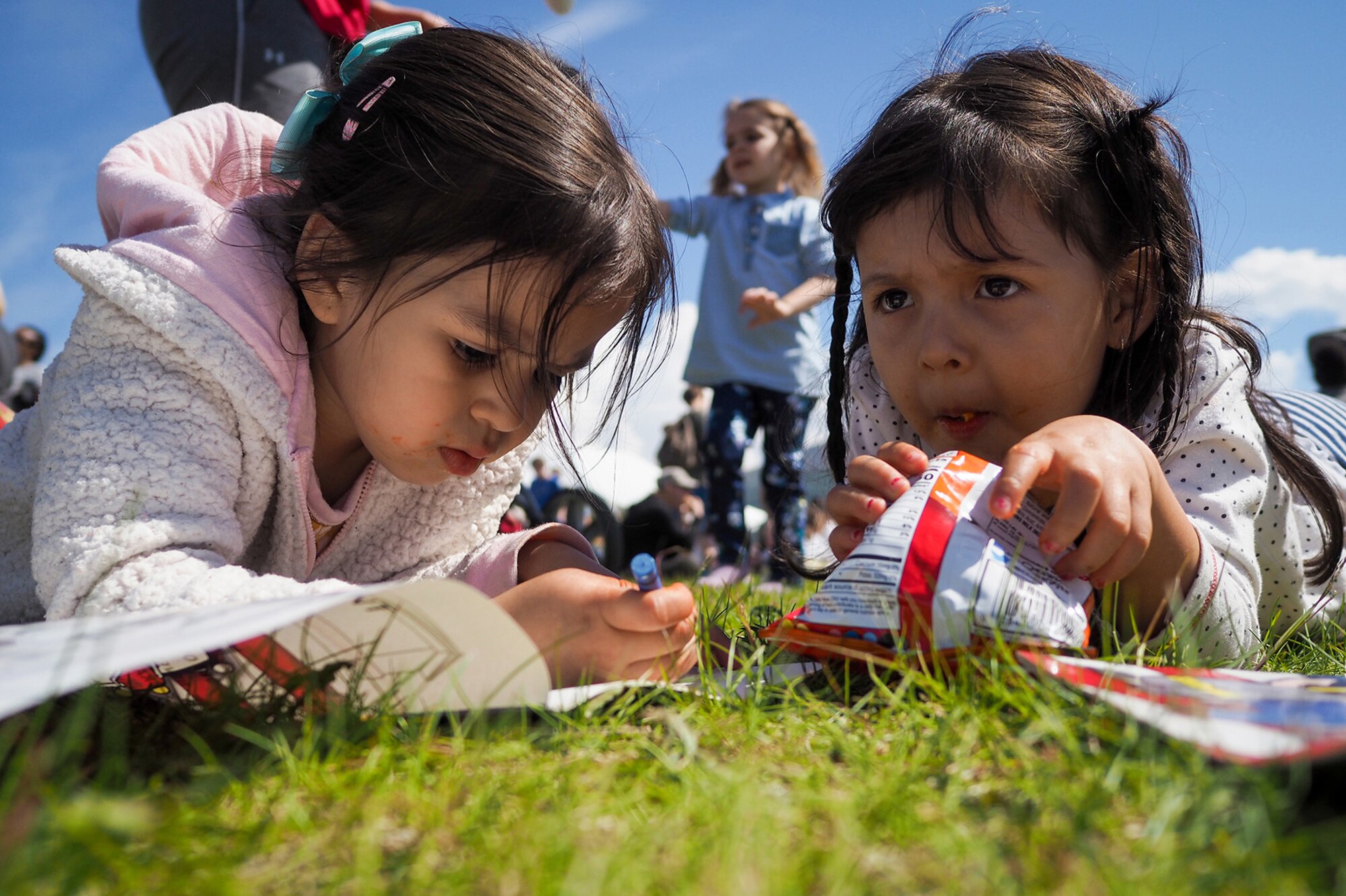 Yaretzy Sandoval, left, and Rebecca Vasquez, both three-years-old, eat food and color at  the Military Appreciation Week picnic at the Joint Base Elmendorf-Richardson, Alaska, Buckner Fitness Center fields June 16, 2017. Several organizations came together to provide a variety of family-fun activities such as competitive sporting events for the adults, face painting and bouncy houses for the children in addition to the Anchorage Chamber of Commerce-provided food and music during the annual event.