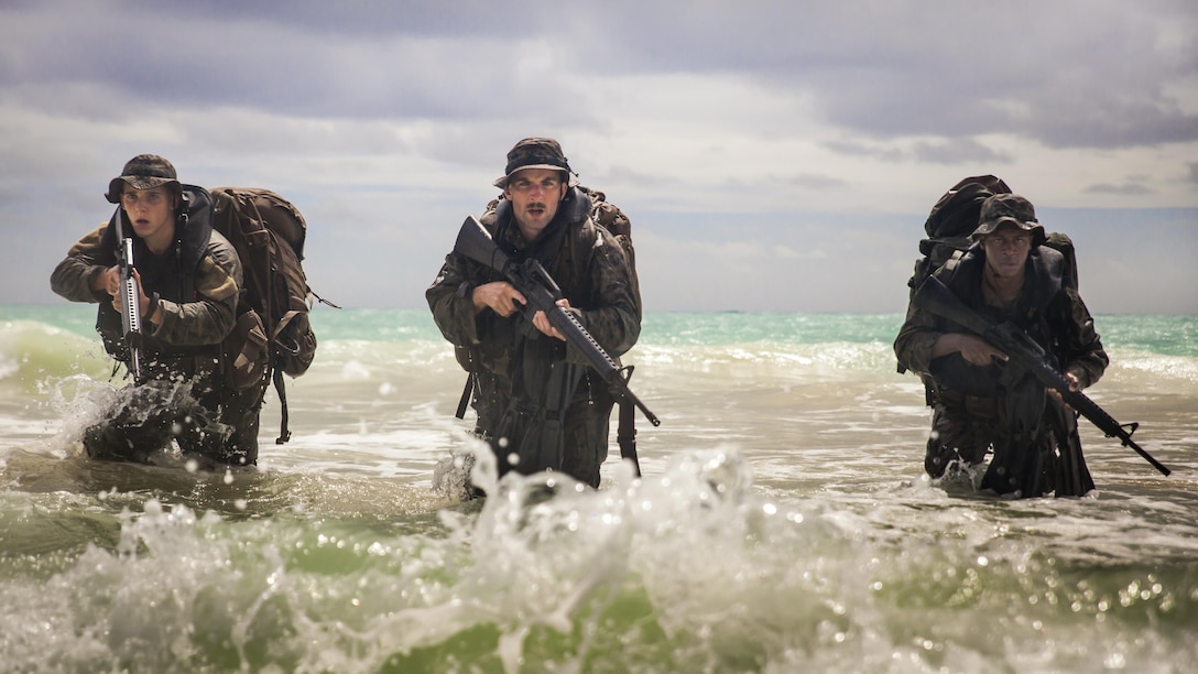 Marine Corps Lance Cpl. Shane Springstead, left, Cpl. Ryan Ehlers, center, and Lance Cpl. Armanie Singletary prepare to take the beach by force during an amphibious exercise at Marine Corps Training Area Bellows, Hawaii, June 15, 2017. The Marines are raider reconnaissance team operators assigned to the 3rd Radio Reconnaissance Platoon, 3rd Radio Battalion. Securing the beach is part of the training during the 13-week reconnaissance raider operator’s course. Marine Corps photo by Lance Cpl. Luke Kuennen