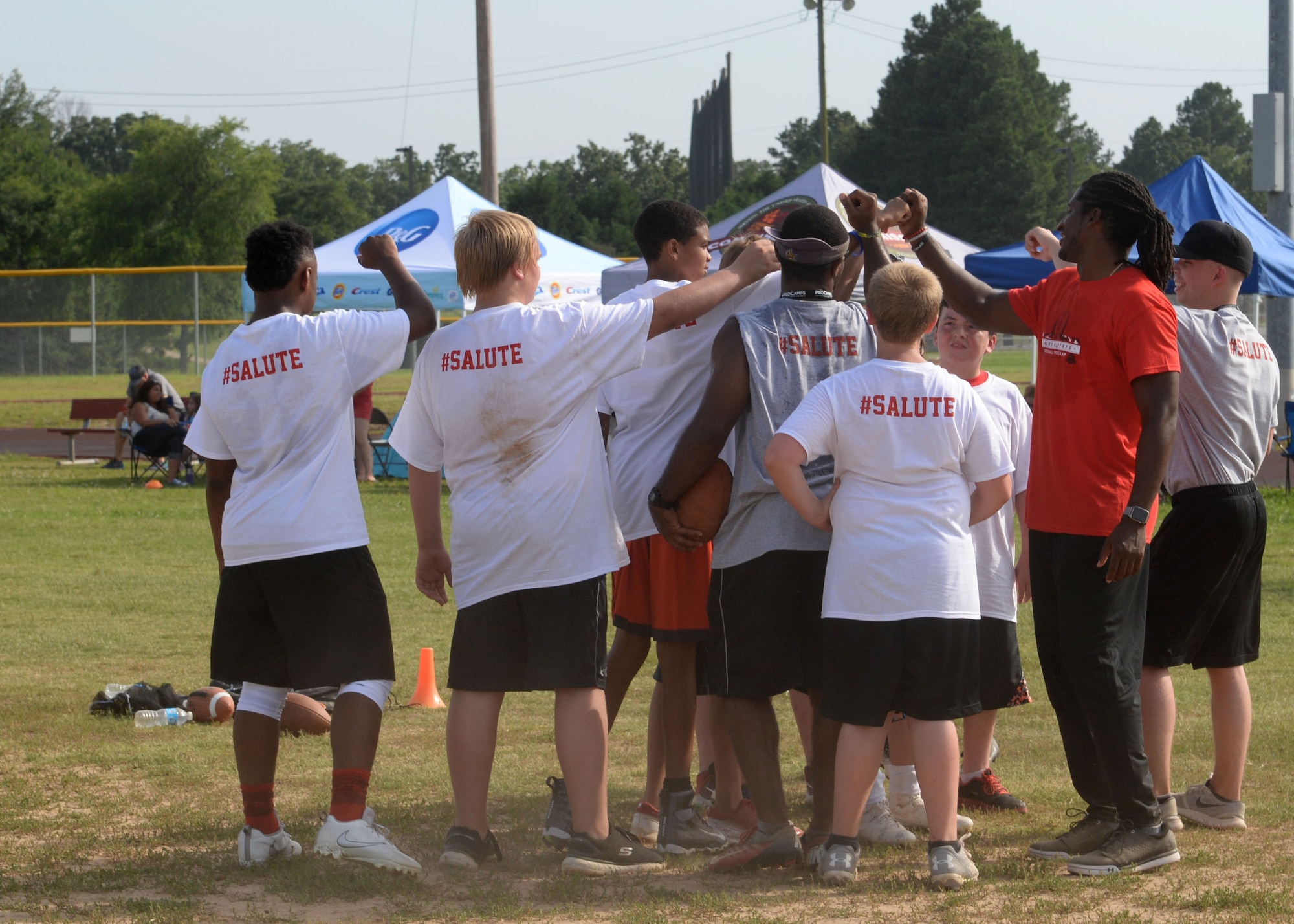 Andre Roberts, an Atlanta Falcons wide receiver and former military child, huddle up after a drill during the Proctor & Gamble Andre Roberts Football ProCamp June 16, 2017, at Little Rock Air Force Base, Arkansas. Andres Roberts worked side by side with volunteers to help teach children different football skills. (U.S. Air Force photo by Airman 1st Class Codie Collins)