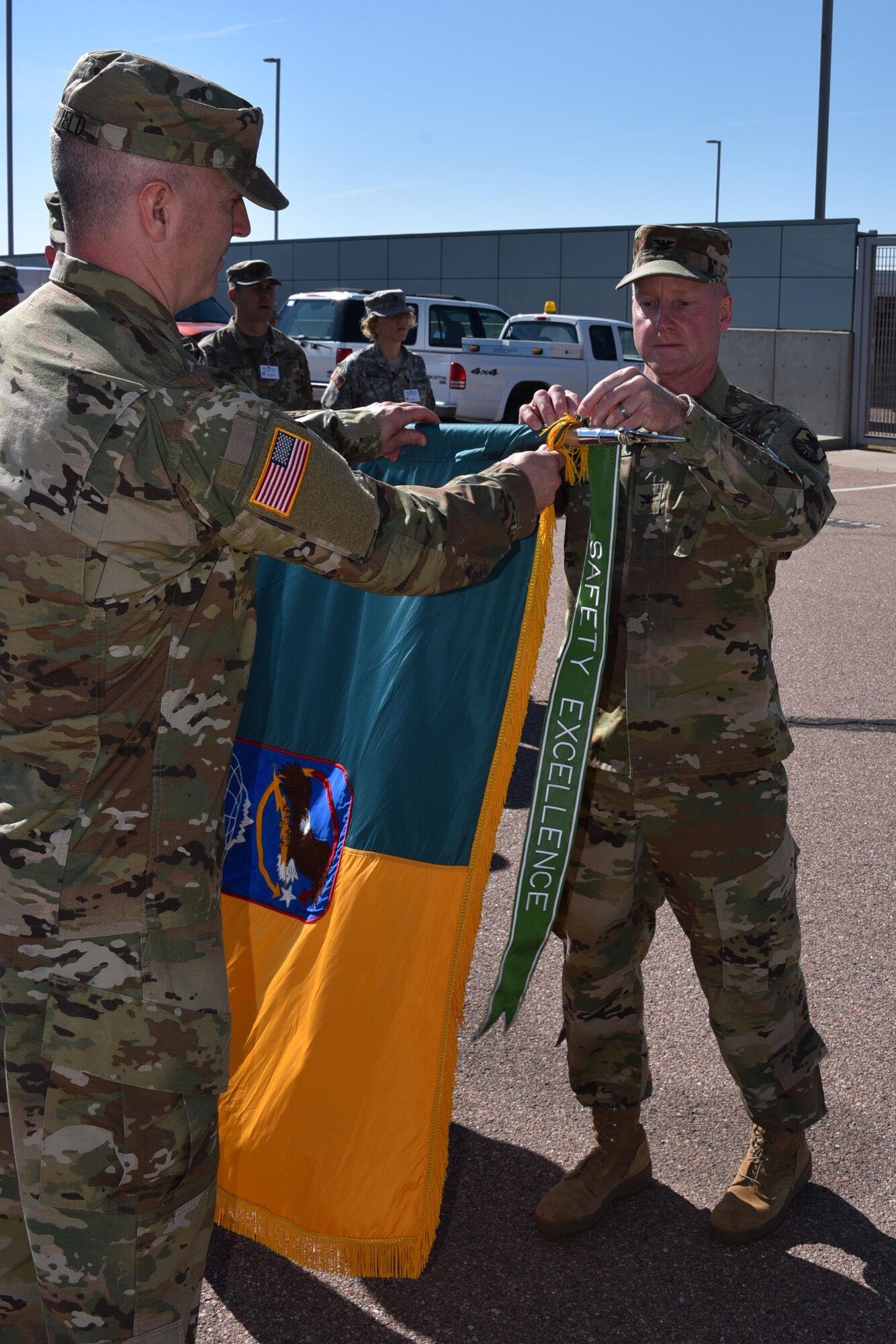 PETERSON AIR FORCE BASE, Colorado --Lt. Col. Michael Hatfield ( left), 100th Missile Defense Brigade S3 operations officer, assists as Col. Tim Lawson, deputy commander for Operations, U.S. Army Space and Missile Defense Command/Army Forces Strategic Command, awards the 2016 Army Safety Excellence Streamer to the 100th MDB during Stand-up for Safety Day, June 8, at the Peterson Air Force Base, Colo., headquarters. (U.S. Army photo by Dottie White)