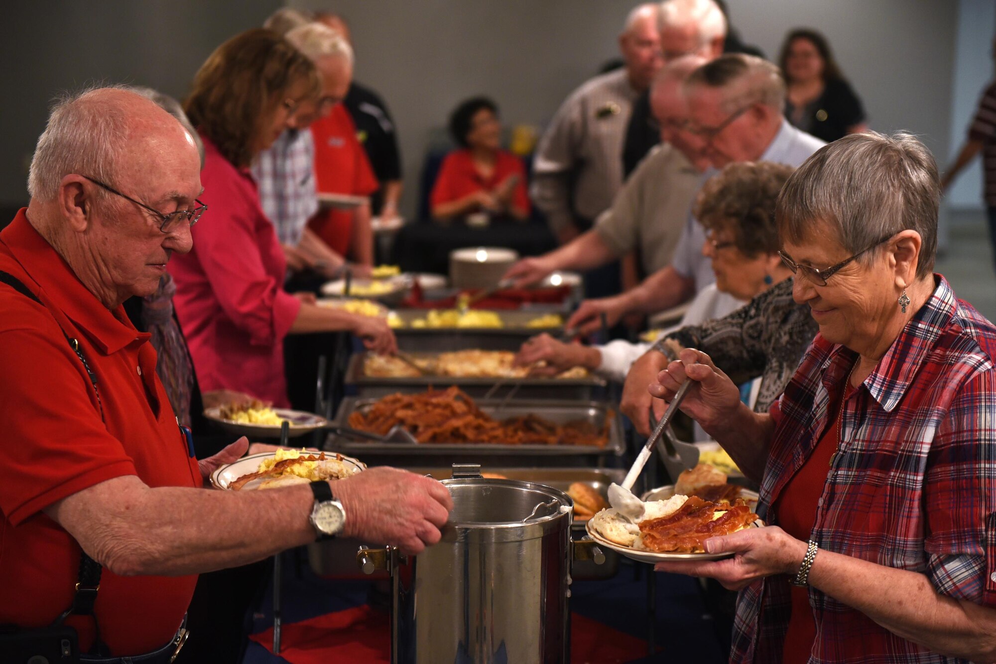 Retired service members and their spouses serve themselves breakfast June 16, 2017, at Hangar 1080 on Little Rock Air Force Base, Ark. The retiree breakfast is held every month to foster close relationships with service members and to disseminate information from units to the retiree community. (U.S. Air Force photo by Airman 1st Class Kevin Sommer Giron)